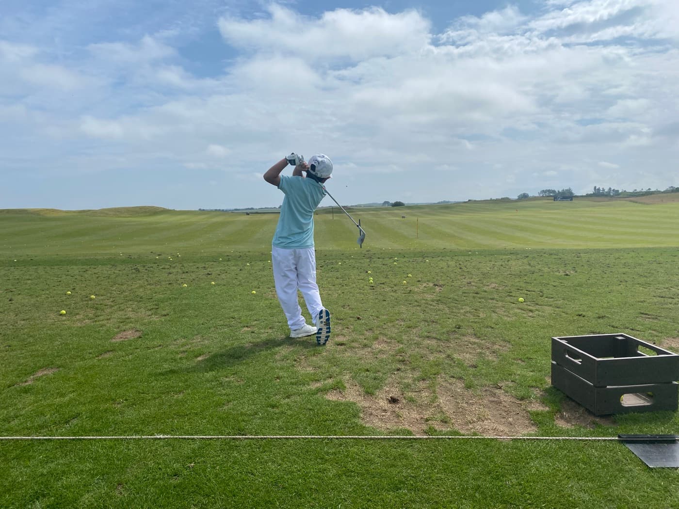 A junior golfer driving off the tee on a links course