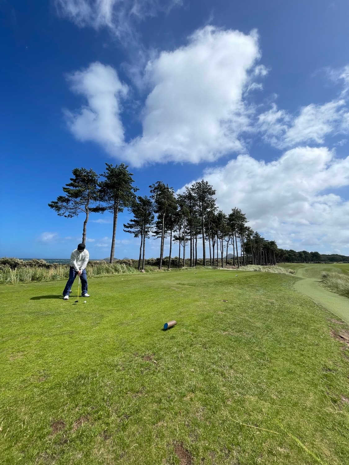 A golfer walking a coastal links under a big sky