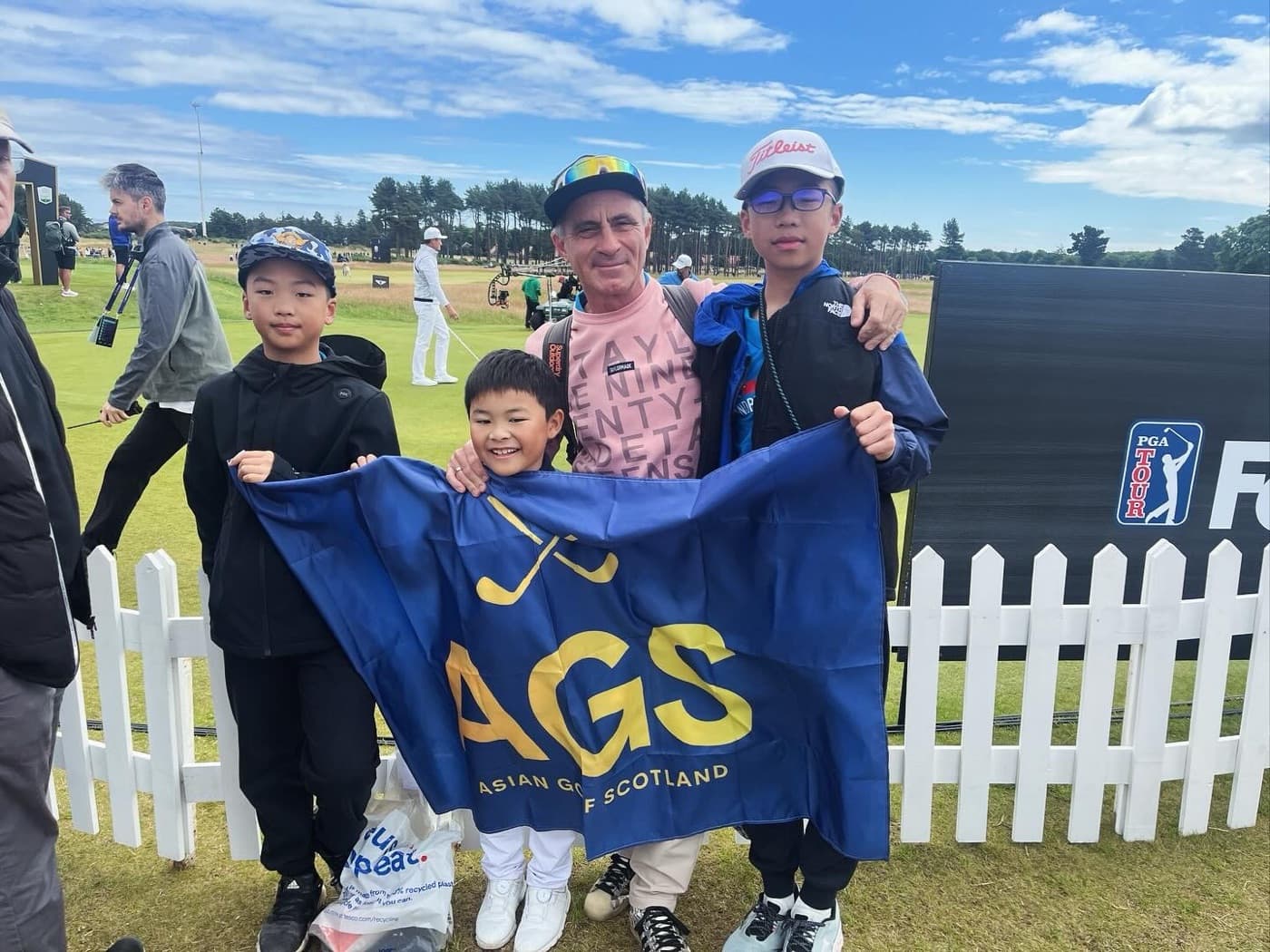 Junior AGS golfers holding the flag by the course